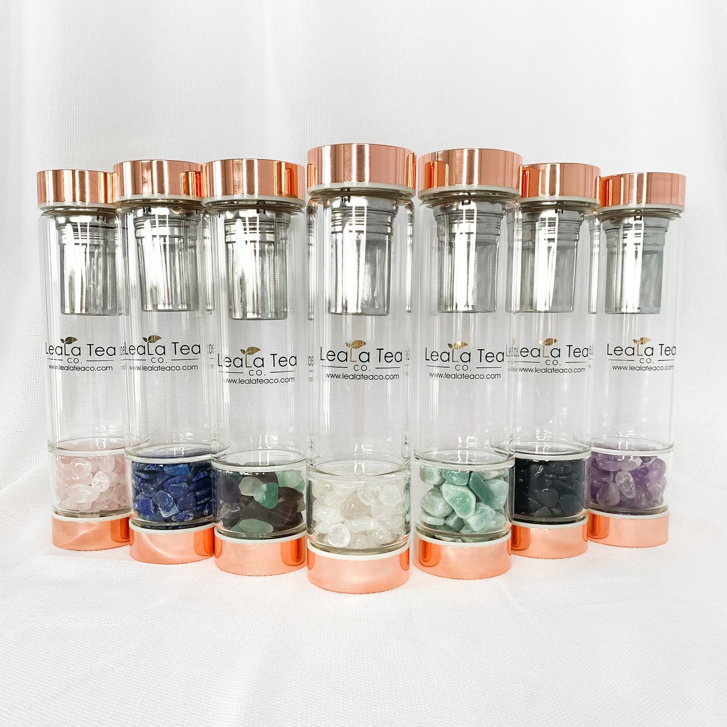 Crystal Tea Infuser Bottle Collection. Left to Right: Rose Quartz, Lapis Lazuli, Coloured Fluorite, Clear Quartz, Aventurine, Black Obsidian, Amethyst.