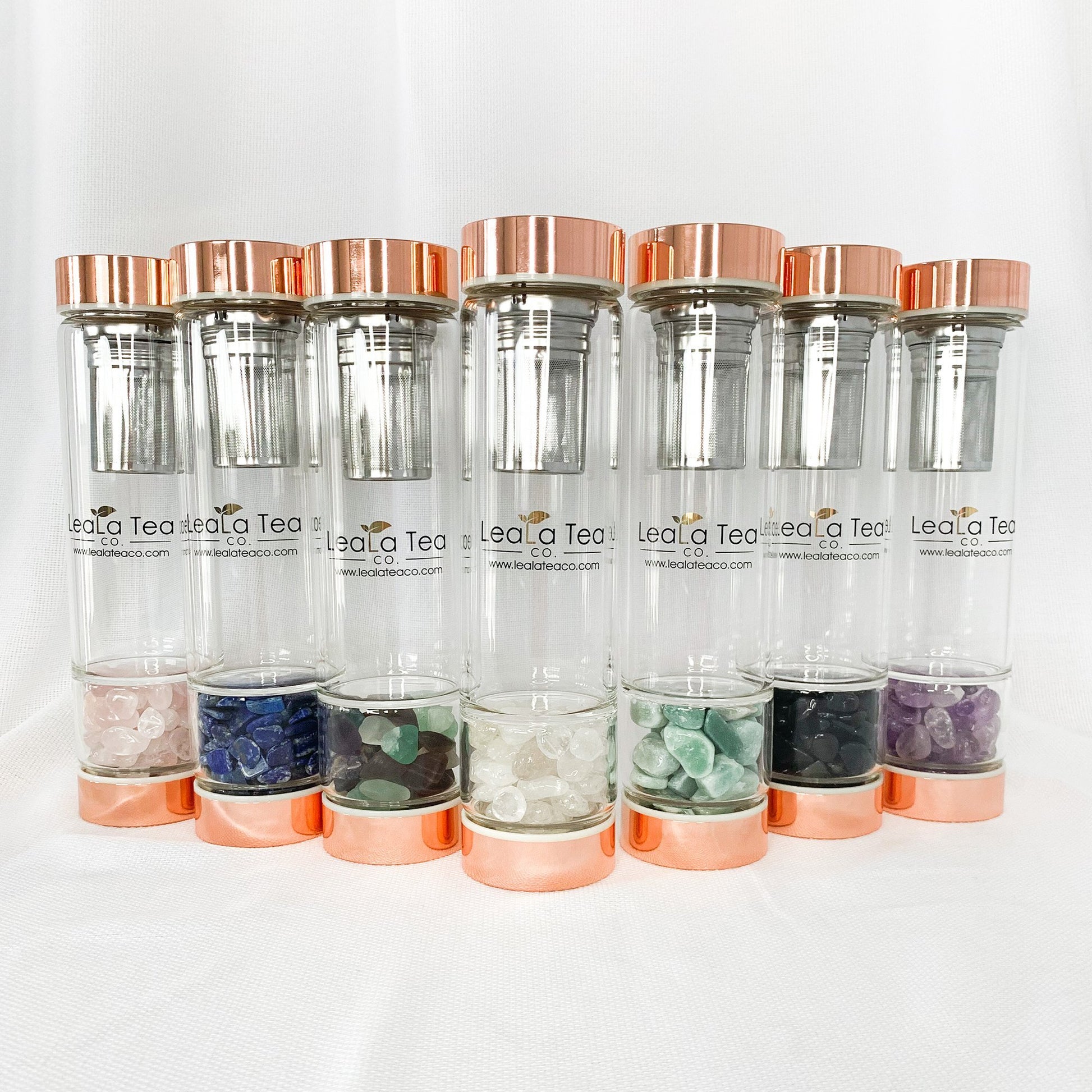Crystal Tea Infuser Bottle Collection. Left to Right: Rose Quartz, Lapis Lazuli, Coloured Fluorite, Clear Quartz, Aventurine, Black Obsidian, Amethyst.
