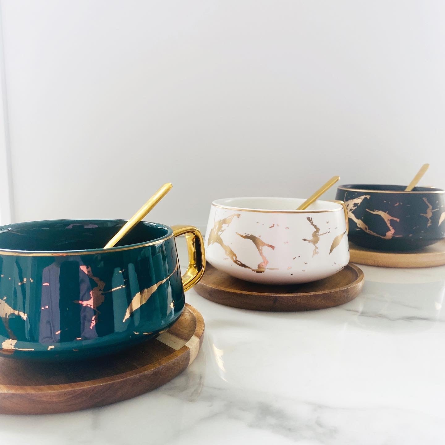 Green and Gold, White and Gold and Black and Gold Boho Luxe Cups lined up with a gold spoon and wooden coaster each.