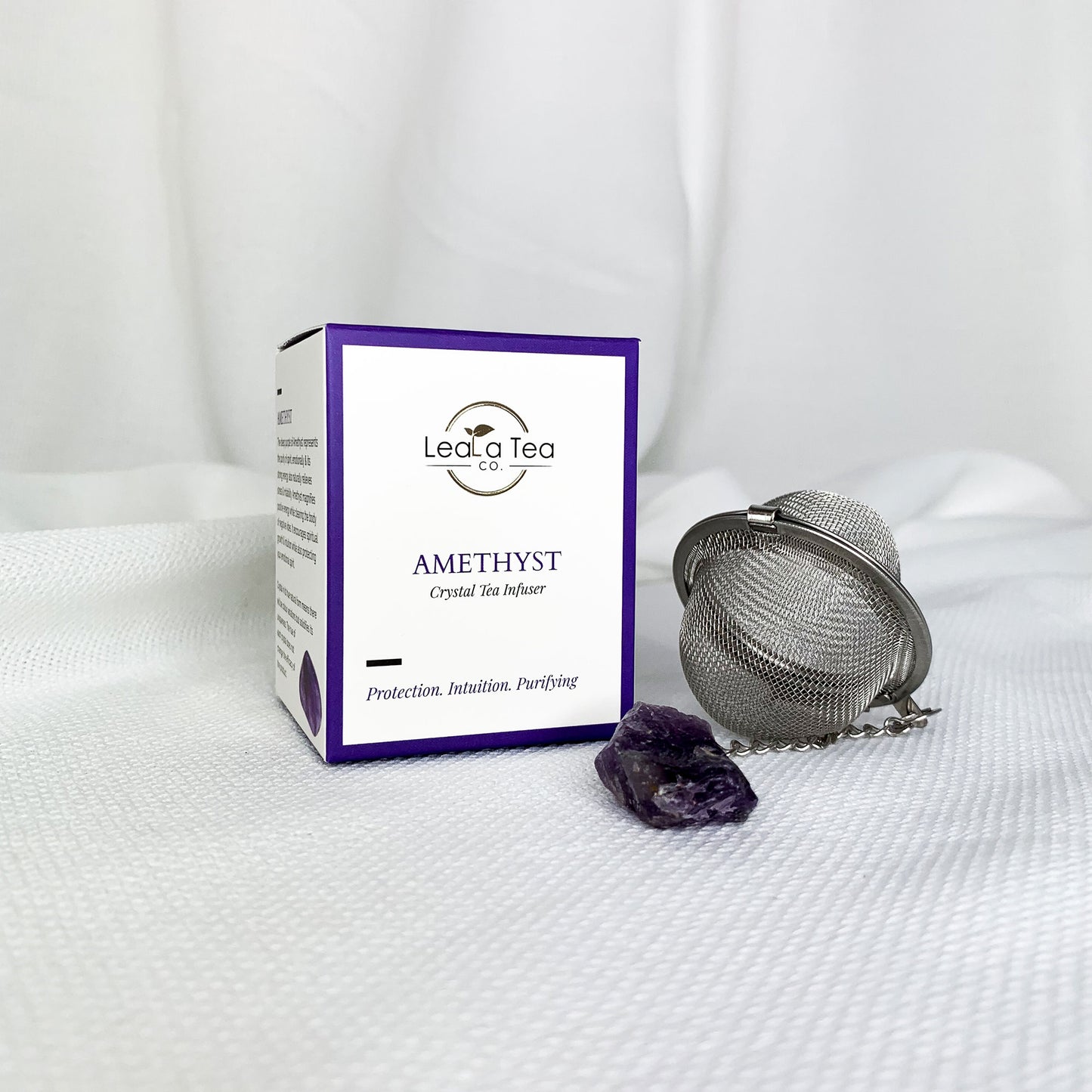 Athella Amethyst Crystal Tea Infuser. Protection, Intuition, Purifying. Box Packaging next to Tea Infuser with natural amethyst crystal. 